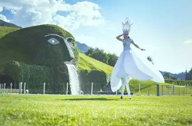 Kunstenaar in wit kostuum op stelten