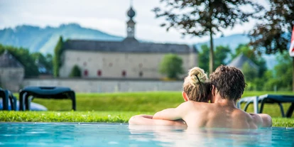 Ausflug mit Kindern - Witterung: Bewölkt - Paar im Außenbecken mit Blick auf Schloss Gabelhofen  - Aqualux Therme Fohnsdorf