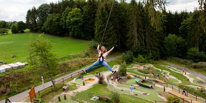 Ausflug mit Kindern - Ausflugsziel ist: ein Naturerlebnis - Sankt Thomas (Eifelkreis Bitburg-Prüm) - Langeweile adé und herzlich willkommen Abenteuer! Inmitten der Vulkaneifel kannst du einzigartige Abenteuer genießen. Erlebe eine atemberaubende Zipline-Tour in der Eifel, wo du von Baumwipfel zu Baumwipfel schwingst, herausforderne Spiele auf unserer Adventure-Minigolf-Anlage, actiongeladener Spaß bei einer Runde Fußball-Billiard, gemütliche querfeldein Turniere beim Cross-Boule, unvergessliche Nächte im Baumzelt „Träumen in den Bäumen“, spannende Outdoor-Teambuildings, erstklassige Übernachtungen in Kuschel- und Adventure-Suiten, Appartements und unserer Ferienwohnung. Komm vorbei und rein ins Abenteuer bei EifelAdventures in Berlingen / Rheinland-Pfalz. - Freizeitpark EifelAdventures
