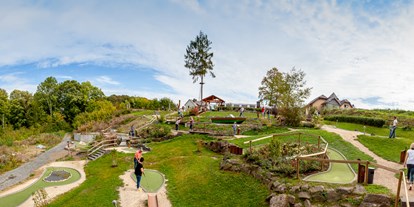 Ausflug mit Kindern - Parkmöglichkeiten - Rheinland-Pfalz - Adventure-Minigolf ist ein Funsport, der Natur, Abenteuer und Sport gekonnt miteinander kombiniert. EifelAdventures bietet auf insgesamt 2.500 qm 18 Bahnen in herrlicher Umgebung. Die gesamte Minigolf-Anlage ist liebevoll in die eifelgeprägte Natur integriert. Alle Hindernisse thematisieren regionale Gegebenheiten. Die Bahnen selbst bestehen aus Kunstrasen. Als Hindernisse dienen überwiegend Naturmaterialien wie Baumstämme, Steine oder Hügel. Durch die Kombination aus spannenden Bahnen und jeder Menge Spaß entsteht ein einzigartiges Erlebnis für Kinder, Teenager und Erwachsene. Also – Schläger in die Hand, und ran an die Bahn. Dein EifelAdventures Team freut sich auf dich! - Freizeitpark EifelAdventures