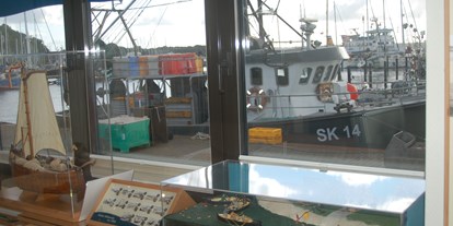 Ausflug mit Kindern - Ausflugsziel ist: ein Museum - Heikendorf - Blick aus dem Infopavillon auf einen Fischkutter im Hafen - Infopavillon Fischereimuseum Heikendorf