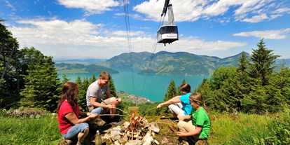 Ausflug mit Kindern - Umgebungsschwerpunkt: Berg - Alpnachstad - Familie beim Picknick auf der Klewenalp. Im Hintergrund die Luftseilbahn Beckenried-Klewenalp - Goldi-Familiensafari
