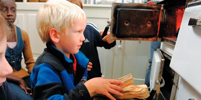 Ausflug mit Kindern - Themenschwerpunkt: Tiere - Deutschland - Ofen anfeuern in der historischen Ausstellung "Alltag der Urgroßeltern" - Kindermuseum Nürnberg