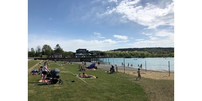 Ausflug mit Kindern - Ausflugsziel ist: ein Bad - Baden-Württemberg - Das Strandbad im Seepark Linzgau im Sommer mit Badegästen. Rechts im Bild ist der Kinderspielbereich zu sehen.  - Strandbad im Seepark Linzgau