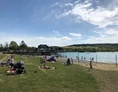Ausflugsziel: Das Strandbad im Seepark Linzgau im Sommer mit Badegästen. Rechts im Bild ist der Kinderspielbereich zu sehen.  - Strandbad im Seepark Linzgau